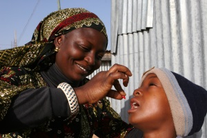 Picture of a women giving a young boy a vitamin A capsule in Nigeria.